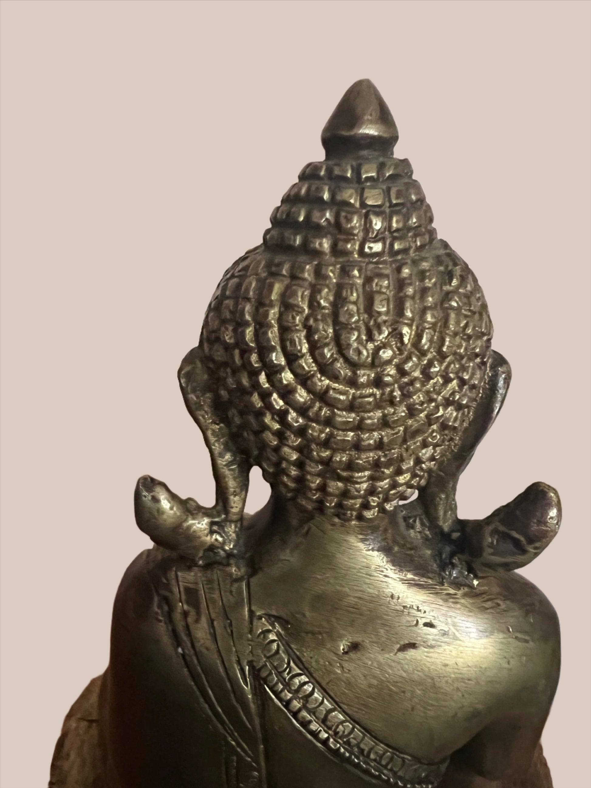A serene Buddha statue from the Saanskrityam Handicraft Store's Buddha Dharma collection elegantly holds a bowl in its lap. Featuring intricate hair curls, elongated ears, and a flame-like ornament atop its head, this piece enhances any Buddha collection. It stands gracefully on a round, decorated base.