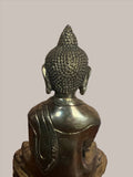 A serene Buddha statue from the Saanskrityam Handicraft Store's Buddha Dharma collection elegantly holds a bowl in its lap. Featuring intricate hair curls, elongated ears, and a flame-like ornament atop its head, this piece enhances any Buddha collection. It stands gracefully on a round, decorated base.