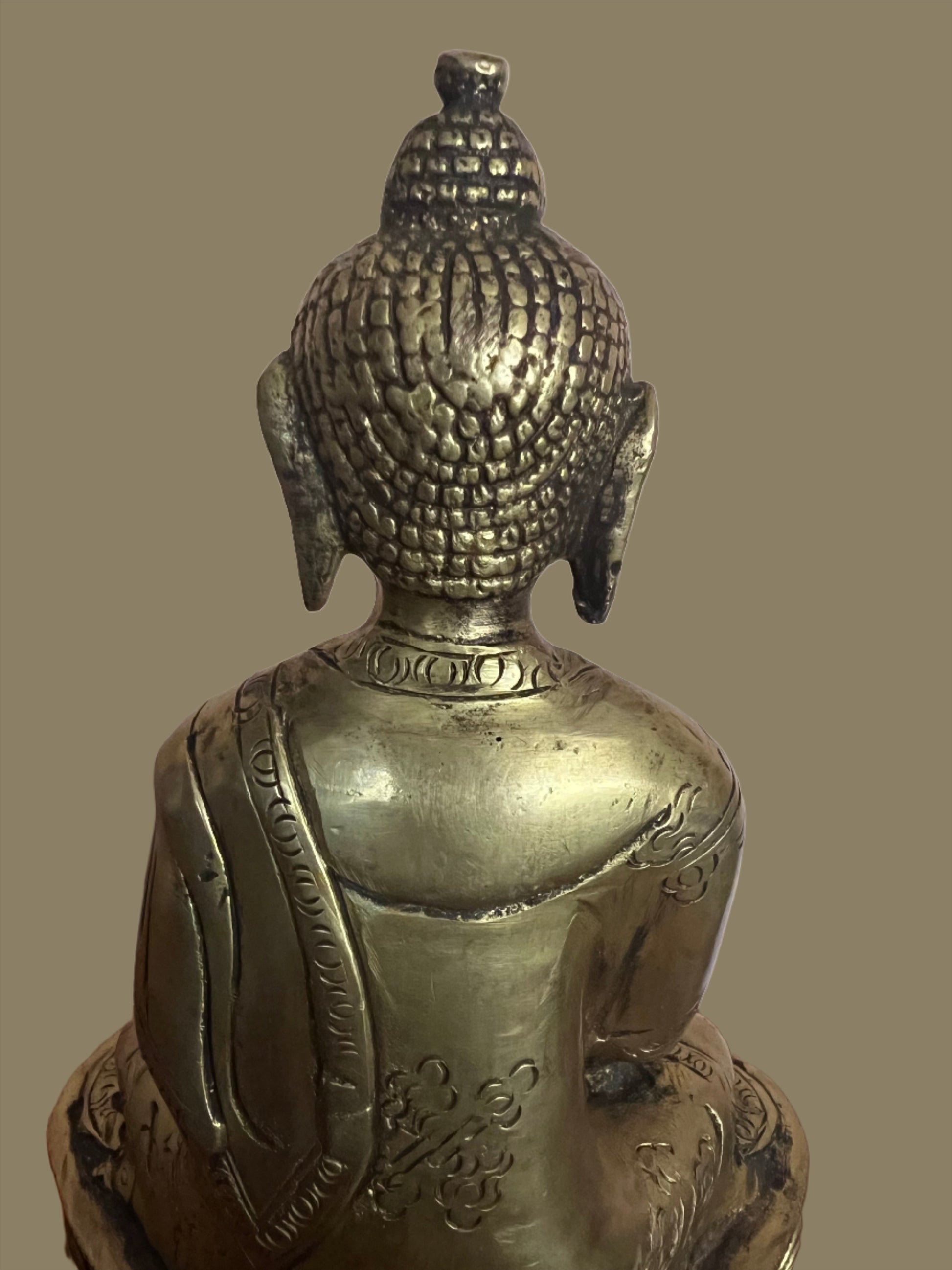A serene Buddha statue from the Saanskrityam Handicraft Store's Buddha Dharma collection elegantly holds a bowl in its lap. Featuring intricate hair curls, elongated ears, and a flame-like ornament atop its head, this piece enhances any Buddha collection. It stands gracefully on a round, decorated base.