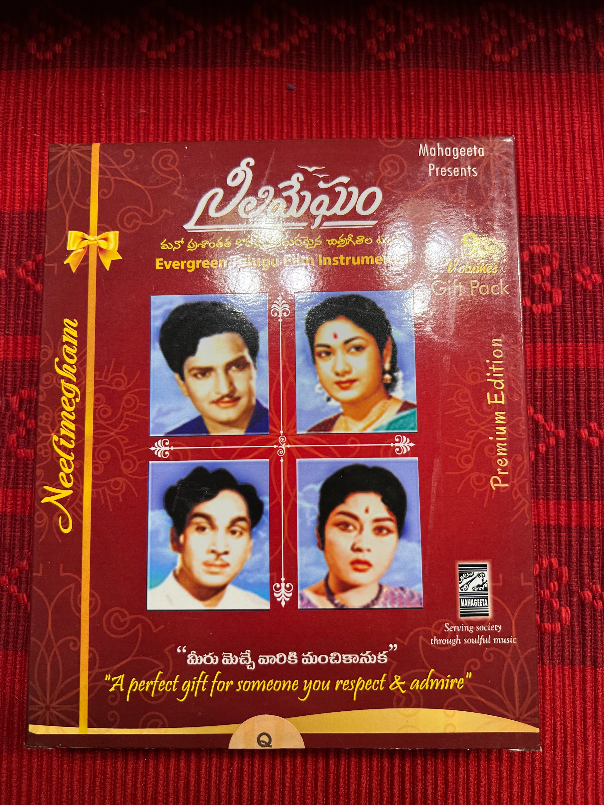 Three packages of the Indian Music Collection incense sticks from Saanskrityam Handicraft Store are arranged on a red fabric. The purple boxes with gold text, featuring an OM symbol and various logos, evoke rich fragrances akin to the soothing notes of Carnatic music.