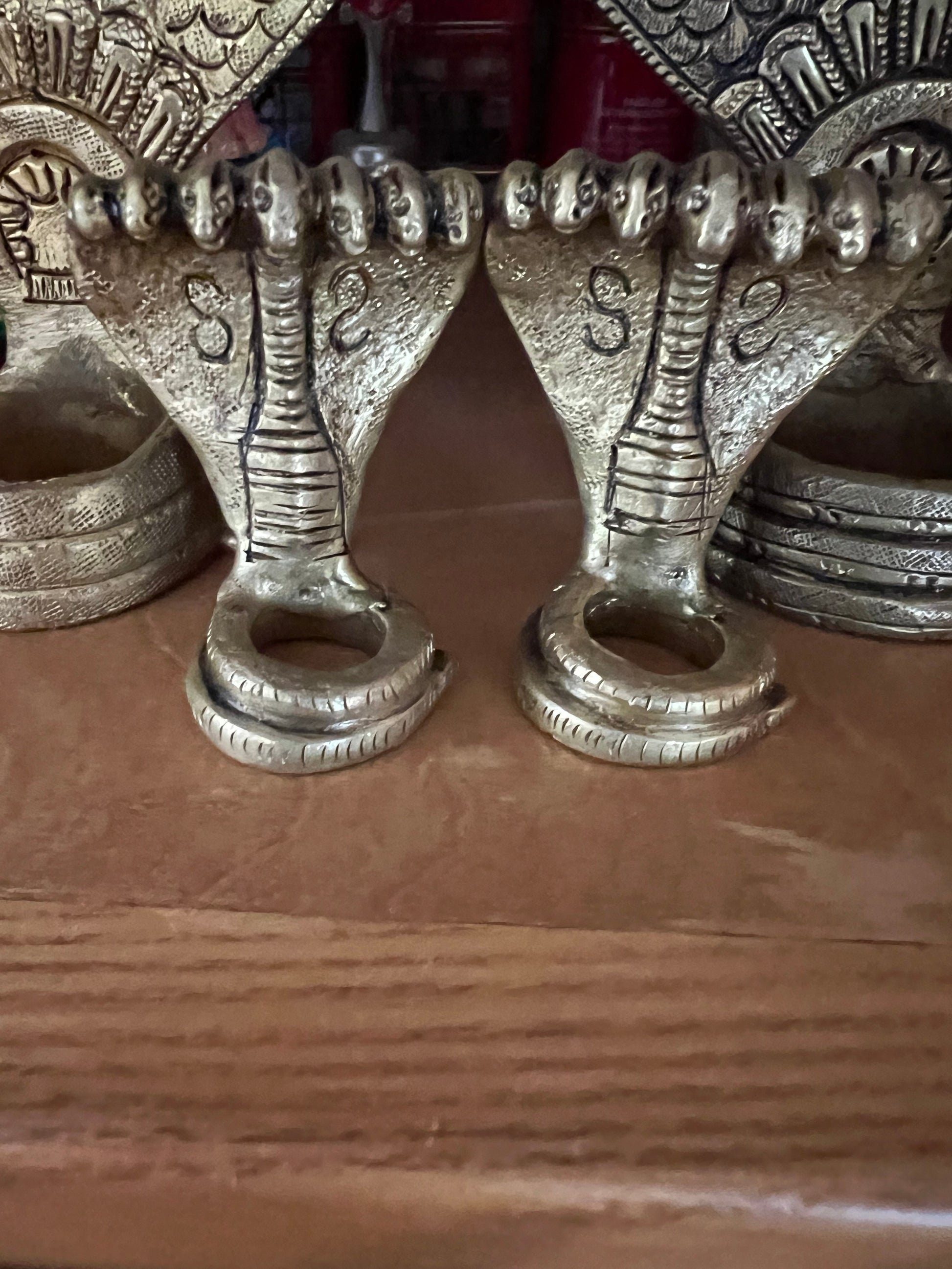 Golden, intricately designed Adisesha Naga bronze sculpture from Saanskrityam Handicraft Store, depicting multiple hooded cobras fanned out like the divine Naga to form a decorative pattern. The plain gray background accentuates the detailed craftsmanship, reminiscent of mythical elegance.