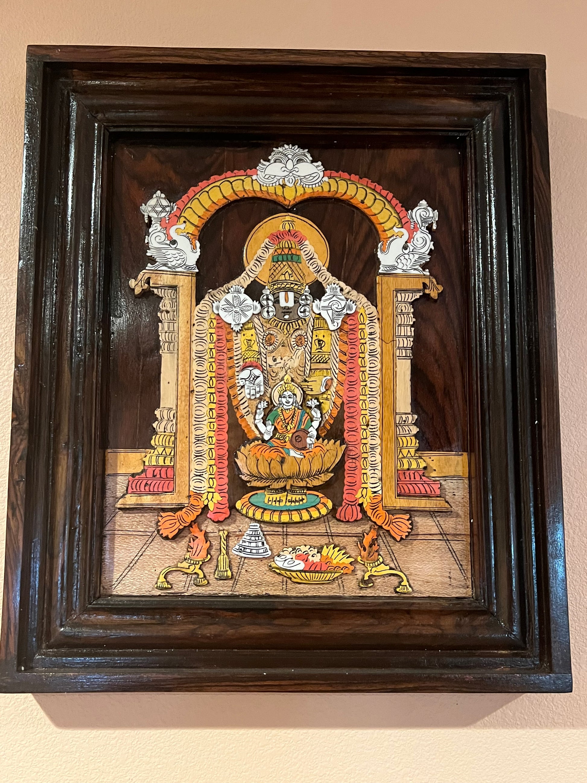 A framed piece of Karnataka rosewood art from the Saanskrityam Handicraft Store depicts a traditional royal procession. The scene includes a chariot with two seated figures, an elephant guided by attendants, and people on foot against a stylized backdrop. The ornate frame is intricately carved from rosewood.
