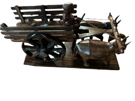 Kerala Kairali Kraft by Saanskrityam Handicraft Store is a wooden model of an ox-drawn cart featuring a seated figure, embodying traditional wood art. It includes large wheels and two carved oxen pulling the cart. The craftsmanship highlights intricate details on both the cart and animals, reminiscent of Divine Wood Ganesha's artistry.