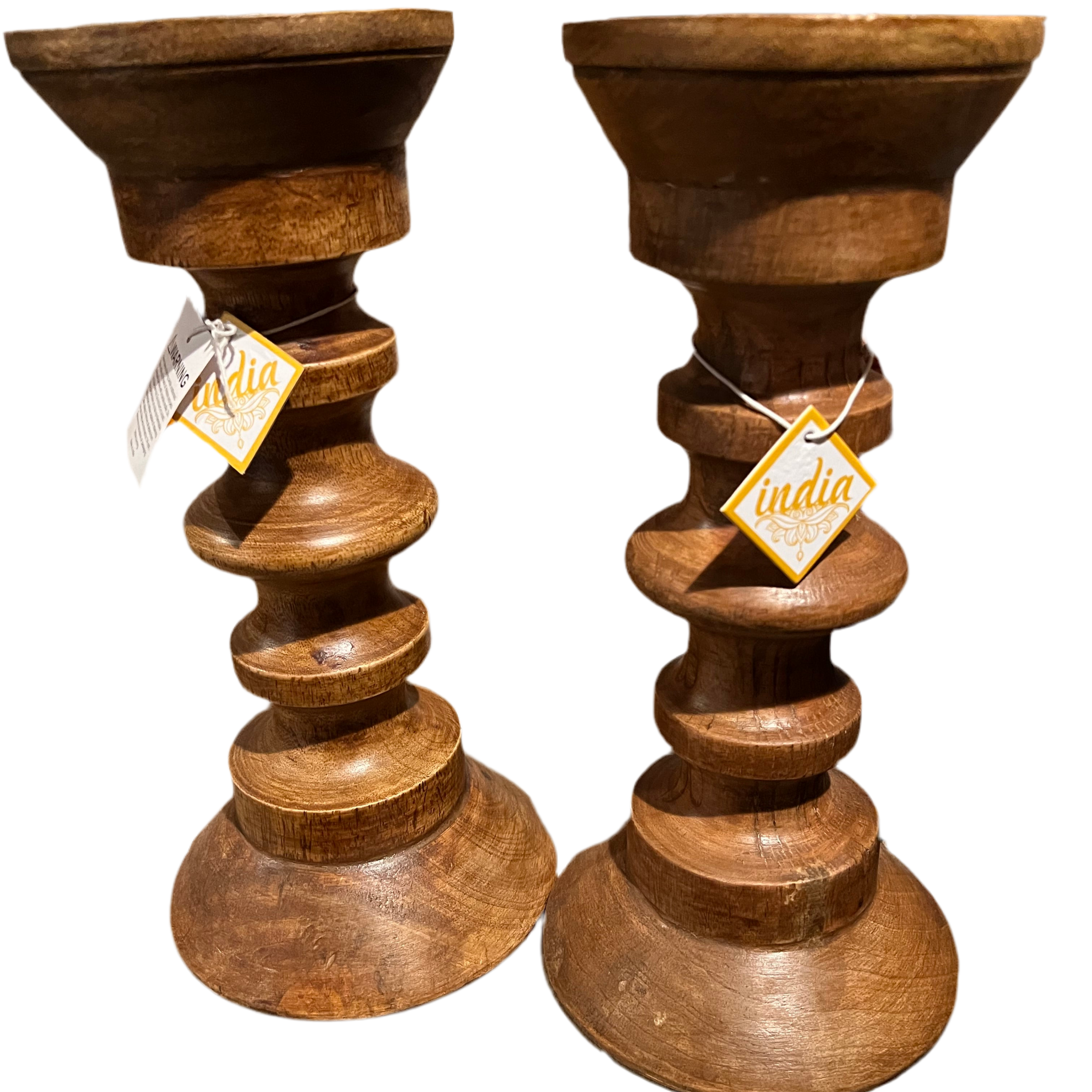 These Holiday Gifts from Saanskrityam Handicraft Store, crafted as wooden candle holders with stacked, rounded sections and tags marked "India," make perfect presents for the holiday season. Arranged on a dark background, they bring a touch of elegance and joy to any celebration.