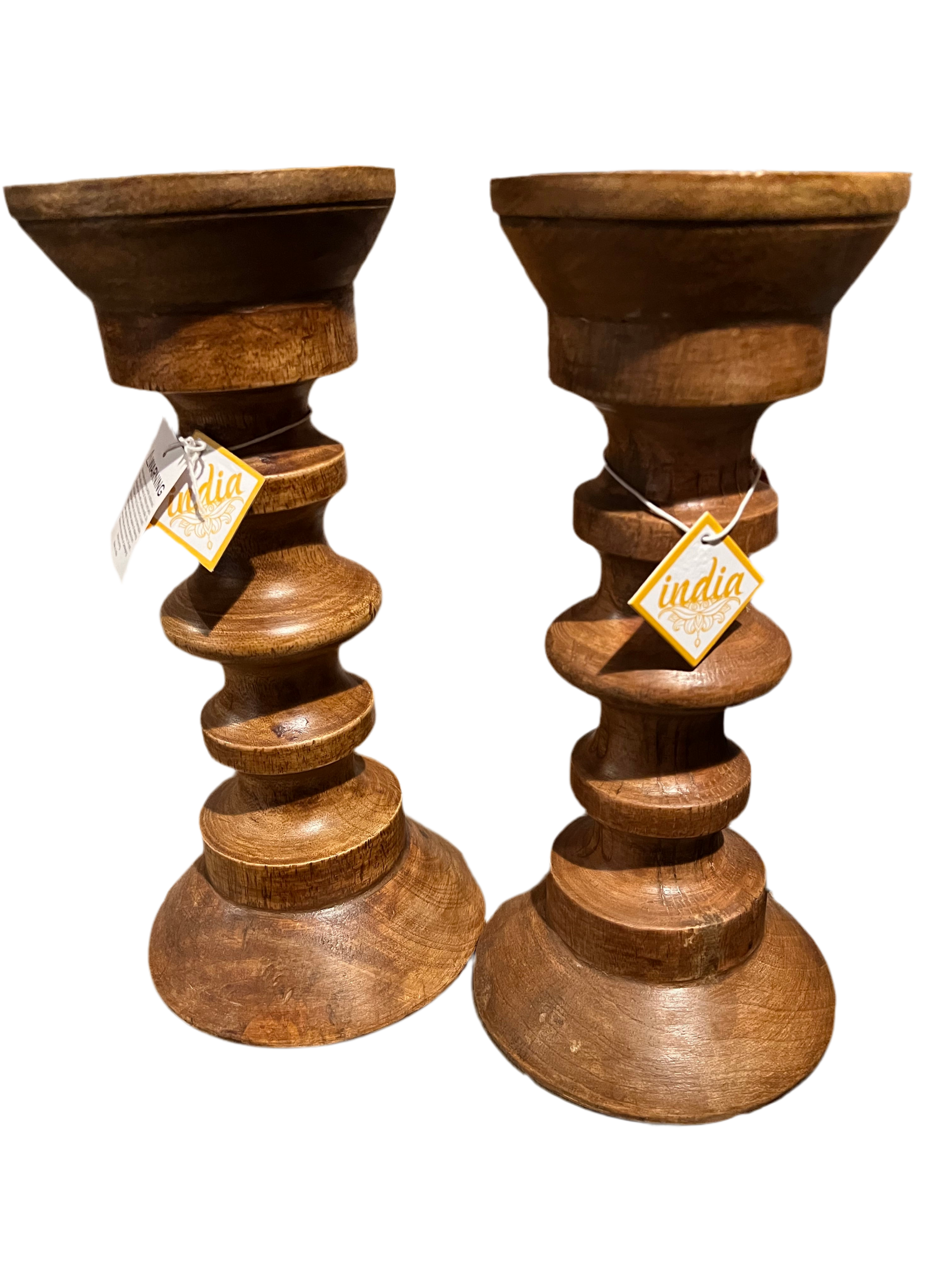 These Holiday Gifts from Saanskrityam Handicraft Store, crafted as wooden candle holders with stacked, rounded sections and tags marked "India," make perfect presents for the holiday season. Arranged on a dark background, they bring a touch of elegance and joy to any celebration.