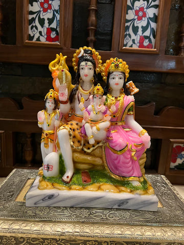 The 8 inch marble Shiv Parivaar statue from Saanskrityam Handicraft Store beautifully portrays the deity family, with a figure holding a trident and another having a smaller figure on their lap. This vibrant piece is adorned with colorful clothing and intricate details, all set on an ornate base.