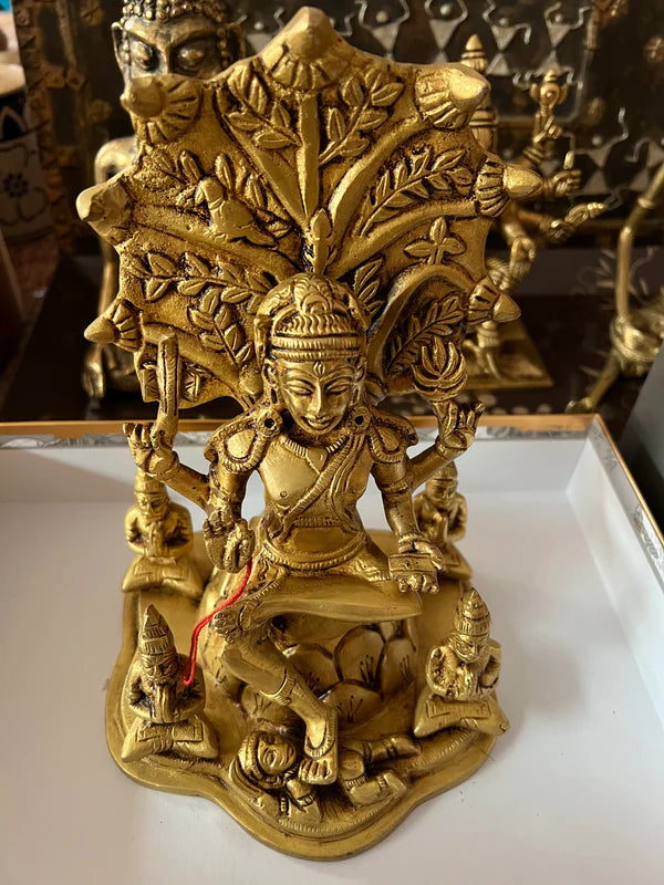 A bronze depiction of Dakshinamurthy from Saanskrityam Handicraft Store, showcasing a multi-armed deity gracefully balanced on one leg upon an ornate base. The 9-inch figure is enhanced with elaborate details, featuring smaller sages and a stylized tree in the background.