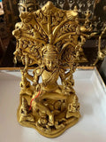 A bronze depiction of Dakshinamurthy from Saanskrityam Handicraft Store, showcasing a multi-armed deity gracefully balanced on one leg upon an ornate base. The 9-inch figure is enhanced with elaborate details, featuring smaller sages and a stylized tree in the background.
