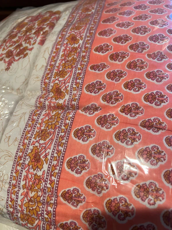 Close-up of the Saanskrityam Handicraft Store's Cream and Pink Queen Comforter. One side showcases intricate floral designs in shades of white, red, and orange, while the other side features a repeated motif of red and orange flowers against a pink background.