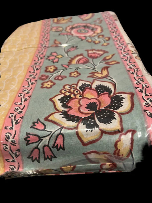 Introducing the "Creamy Yellow and Pink and Maroon Floral" fabric from Saanskrityam Handicraft Store, showcasing floral patterns in pink, yellow, and black set against a green background. This design features pink bands with smaller floral motifs along the edges, highlighted by a large flower as the central focus, all encased in protective plastic.