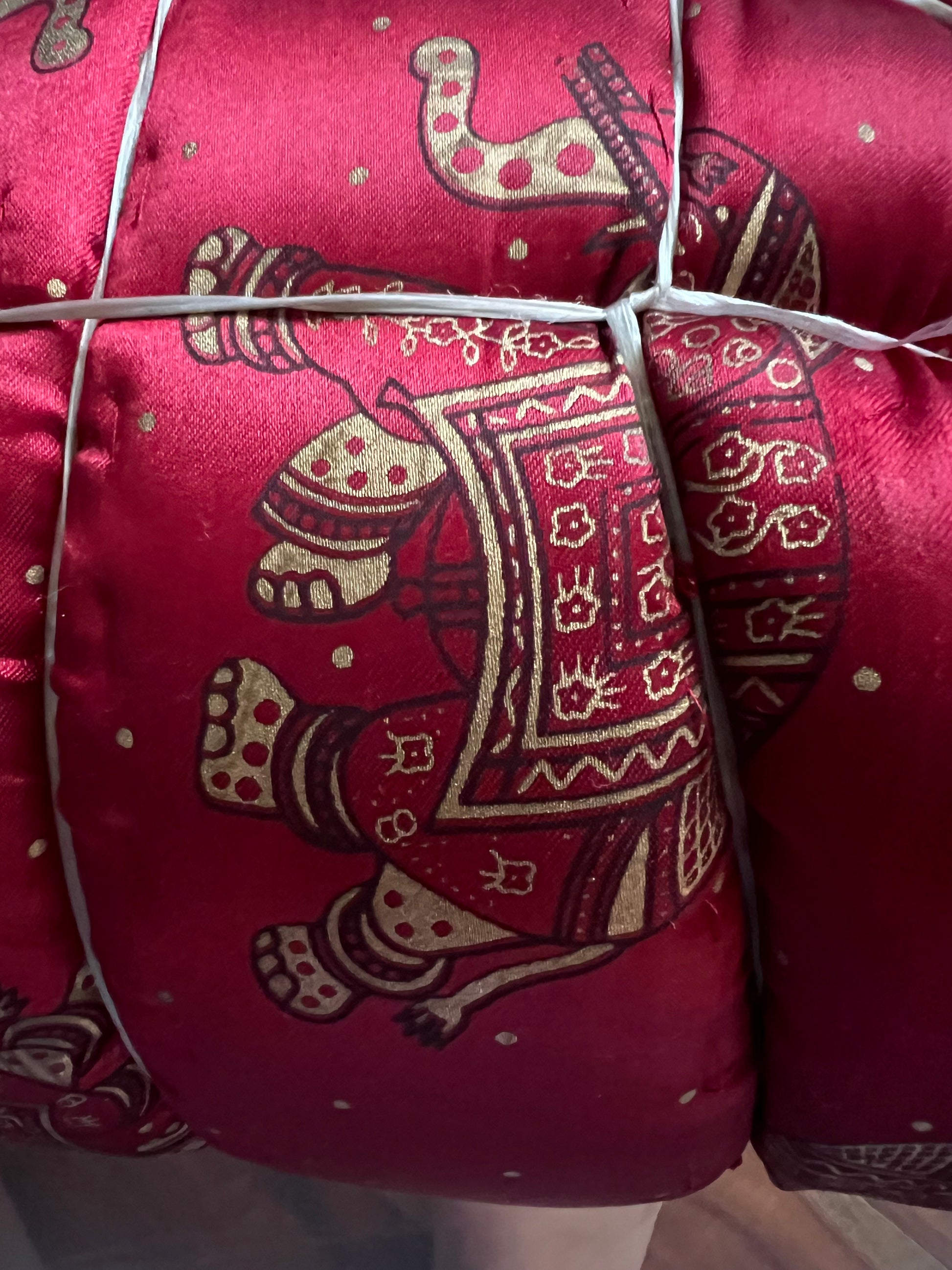 A close-up of the Jaipuri Razai, a cozy queen-size satin comforter by Saanskrityam Handicraft Store, featuring gold elephant designs on a purple background. This exquisite fabric, handmade in Rajasthan, is quilted and secured with white ties.