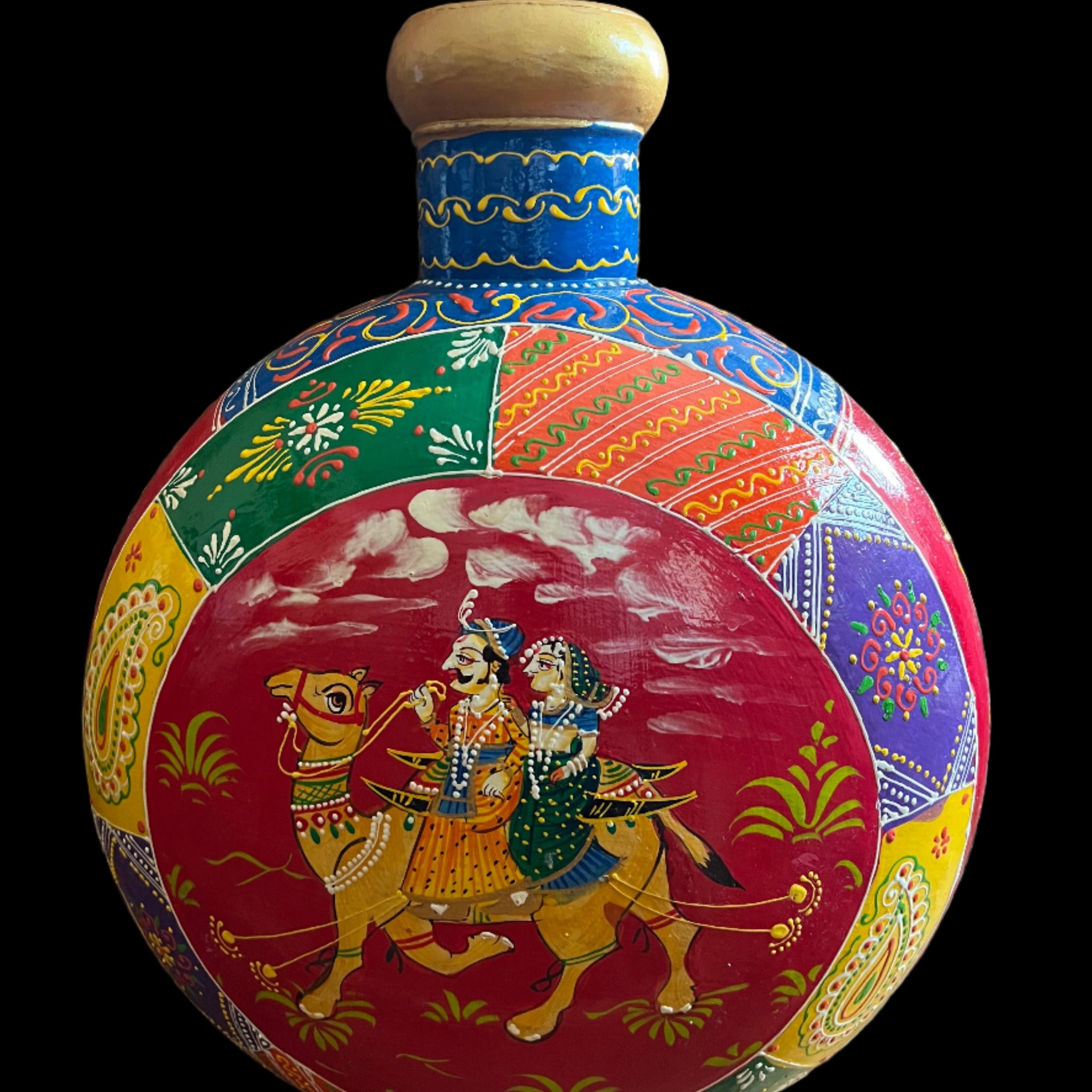 Experience the vibrant beauty of Saanskrityam Handicraft Store's "Rajasthani Art on Metal Vase." This handcrafted piece from India features colorful traditional artwork, with a central image depicting a man and woman in traditional attire riding a camel and intricate patterns in various bright colors surrounding them.