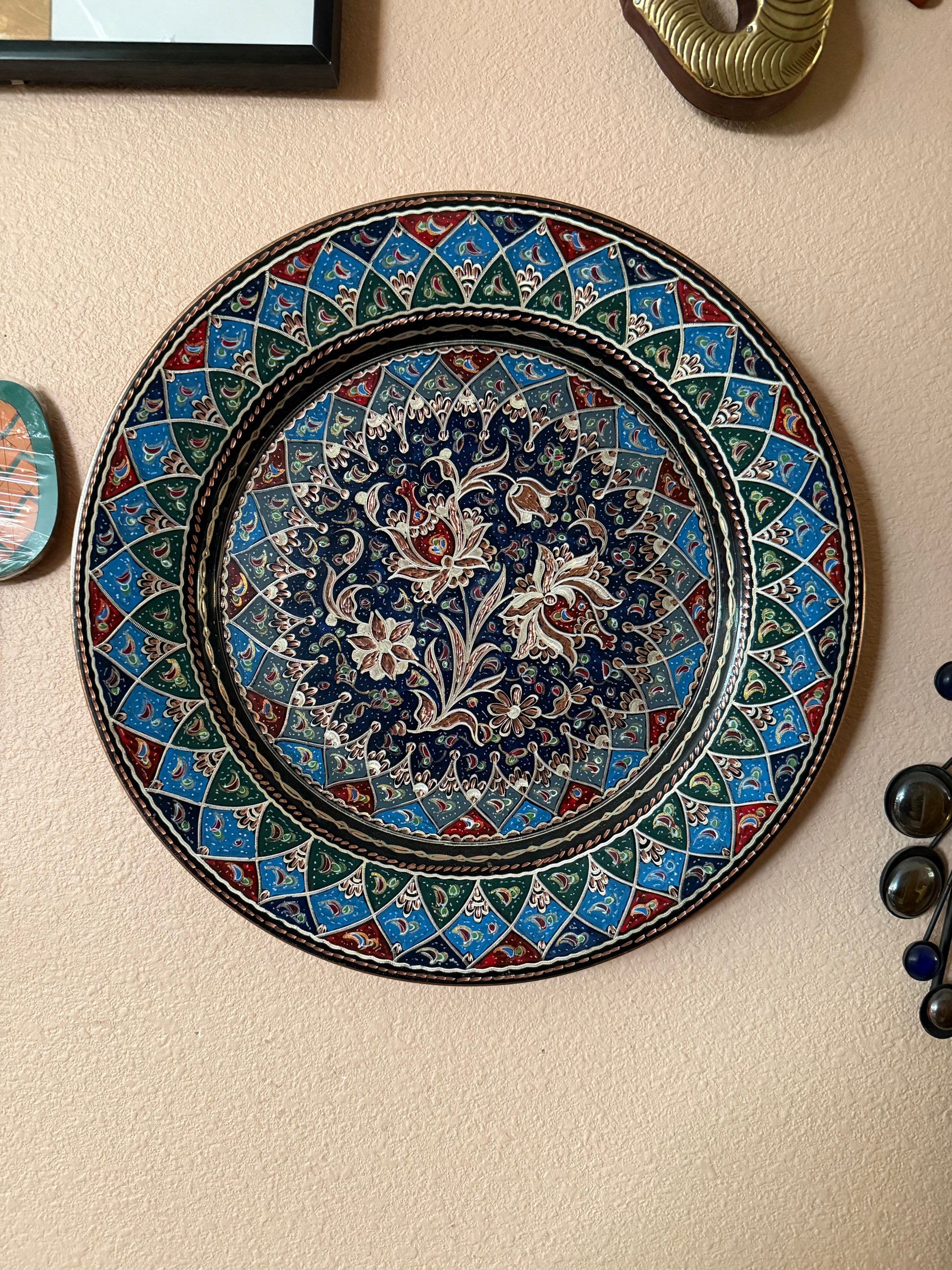 The "Türkiye Treasures" pendant from Saanskrityam Handicraft Store showcases a large decorative blue eye, also referred to as an evil eye warder. It is adorned with intricate metal detailing and smaller blue eye motifs encircling a circular frame, inspired by traditional Turkish designs. The pendant features an ornate hanger at the top for added elegance.