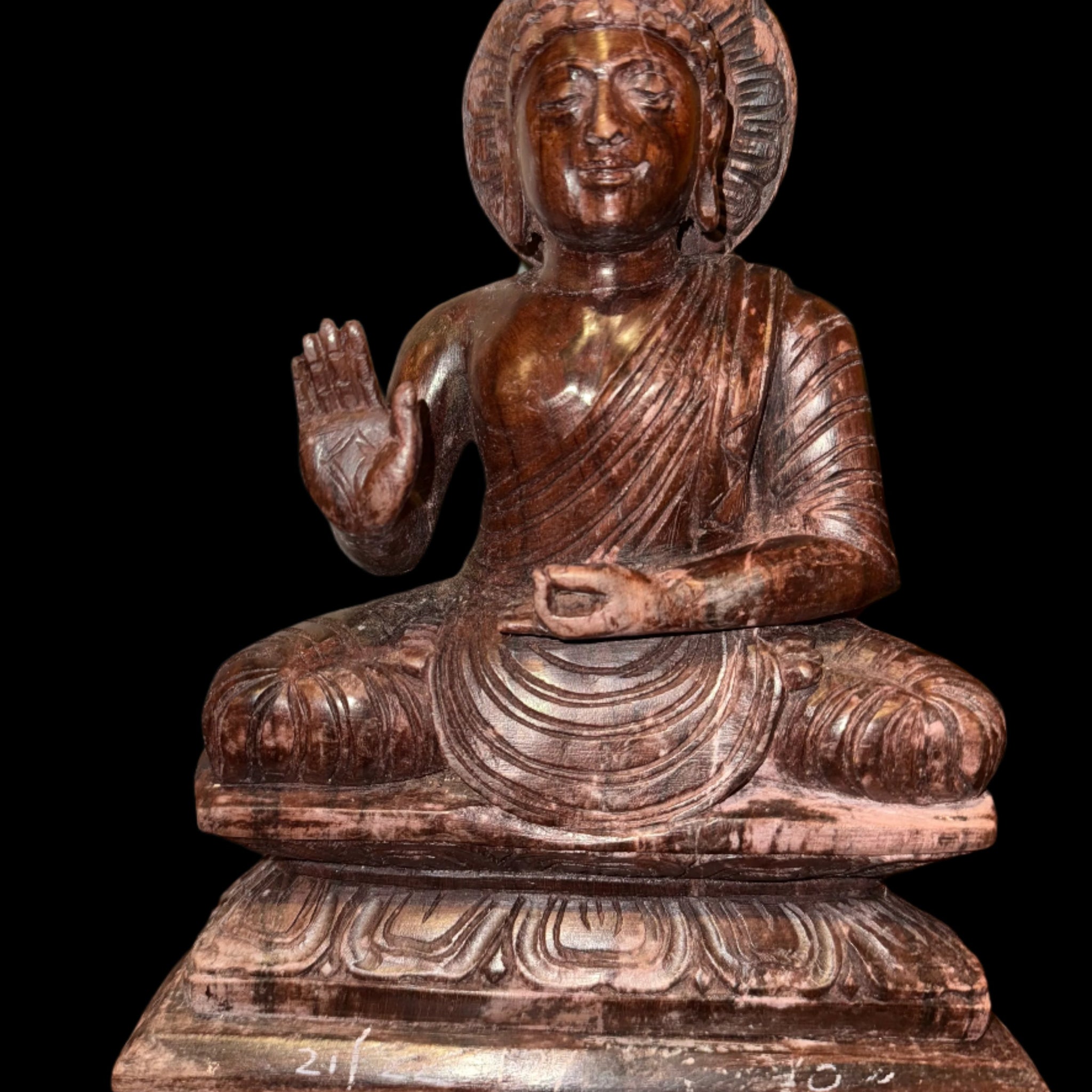 Introducing the 11-inch Buddha crafted from mixed wood grain by Saanskrityam Handicraft Store. This statue showcases a seated Buddha with an ancient aesthetic that enriches its serene expression. The intricate carvings, with one hand raised in a blessing gesture, are elegantly set against a black background.