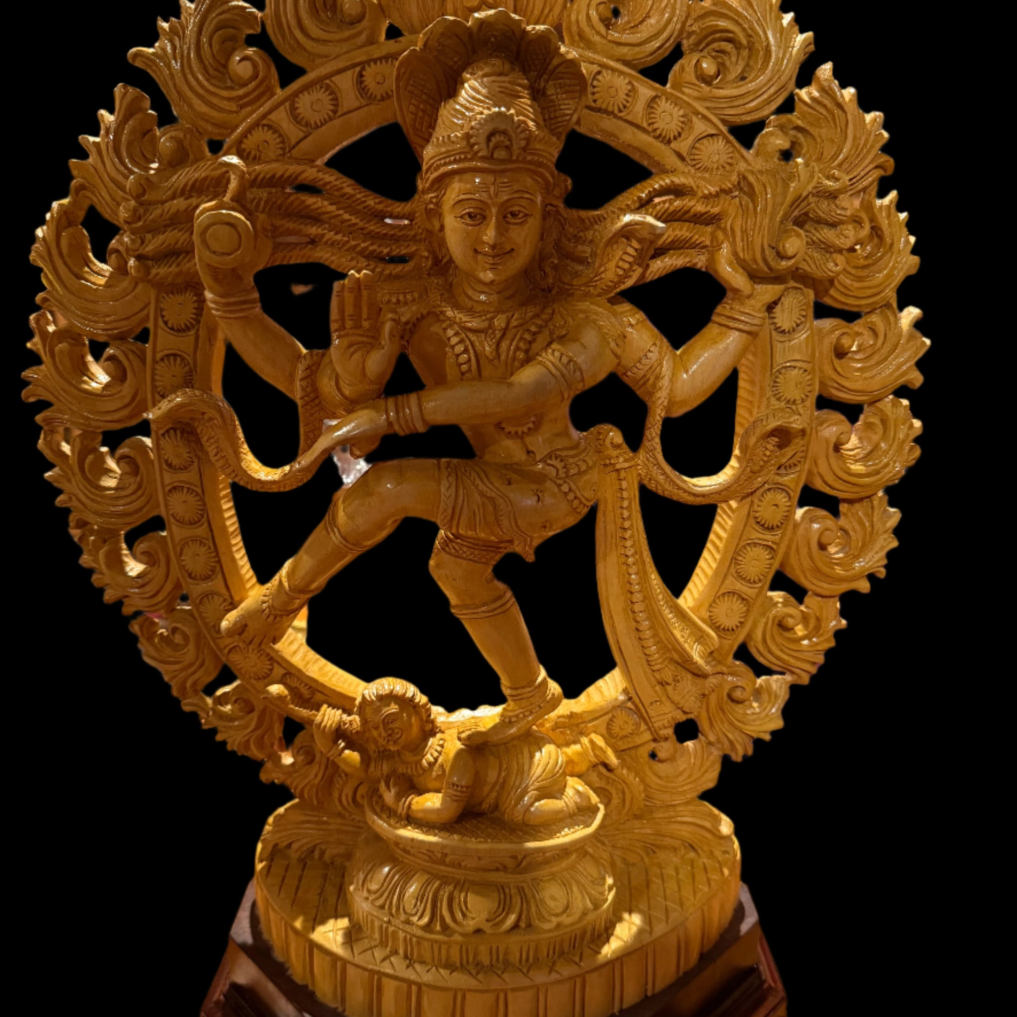 The "Wood Nataraja 20 inch" by Saanskrityam Handicraft Store is a handmade golden statue of a dancing figure, possibly Lord Shiva as Nataraja. The collectible piece features an intricate ornamental halo and stands elegantly on a circular base atop a dark wooden pedestal.