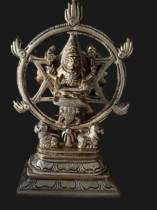 Product Description: The Narasimhaswamy with Chakratthuazhwar idol by Saanskrityam Handicraft Store is a stunning brass statue featuring a deity seated within an ornate circular frame. This intricately detailed piece includes two animal figures at the base and is adorned with decorative elements that beautifully enhance the central figure.