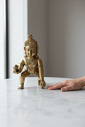 Laddoo Gopal Baby Krishna brass statue next to a hand for scale reference — 14 inch size comparison