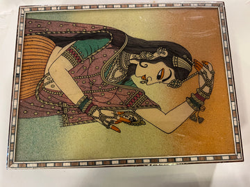 The "Women's gifts Saanskrityam" by Saanskrityam Handicraft Store features a vibrant painting of a woman in traditional attire, embellished with bangles and jewelry, lying on her side like a Meenakari jewel box. The woman rests her head on her hand amidst intricate patterns and vivid colors that evoke the essence of Madhubani art.