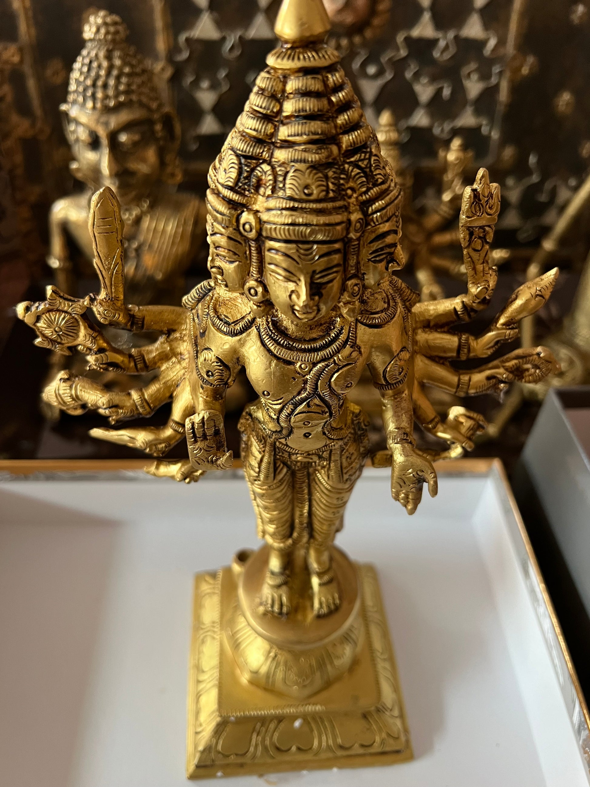 Arumugam, the 6 faced Lord Kartikeya, divine commander,giver of prosperity and courage, has multiple arms and a weapon or divine object in each arm. Textured  divine beauty is abundant in this bronze sculpture